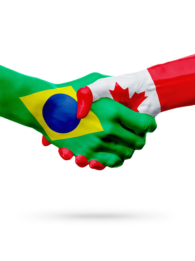 Aperto de mãos pintadas nas cores das bandeiras do Brasil e do Canadá.